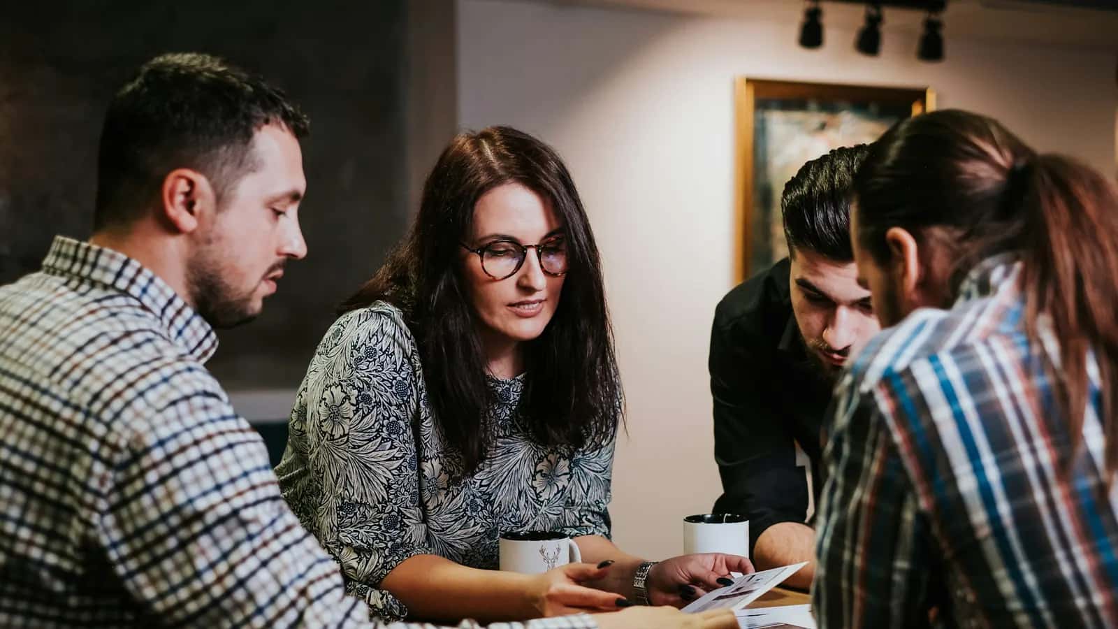 Équipe de quatre personnes examinant ensemble des documents autour d'une table
