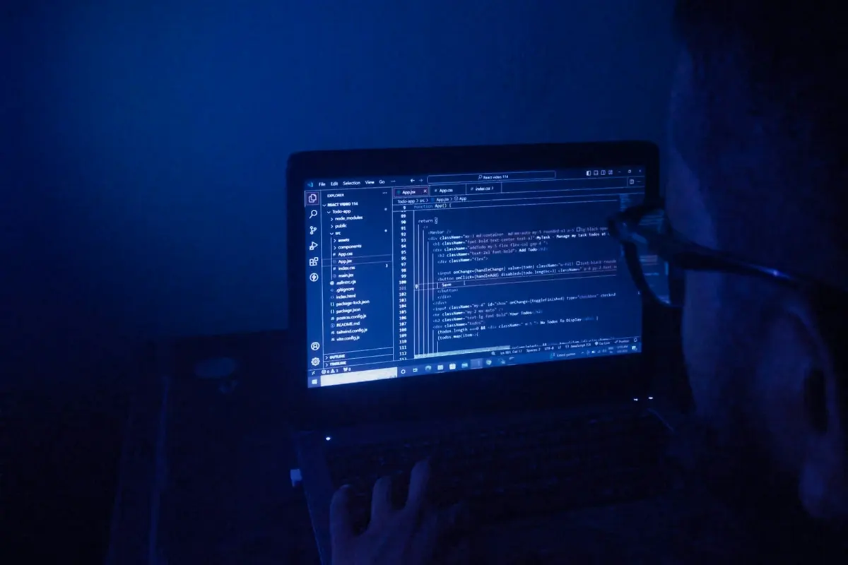 Écran d'ordinateur portable affichant du code dans une pièce plongée dans le noir